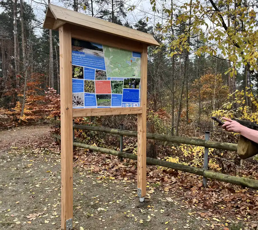 Tafel mit Holzgestell und bedruckter Platte im Wald